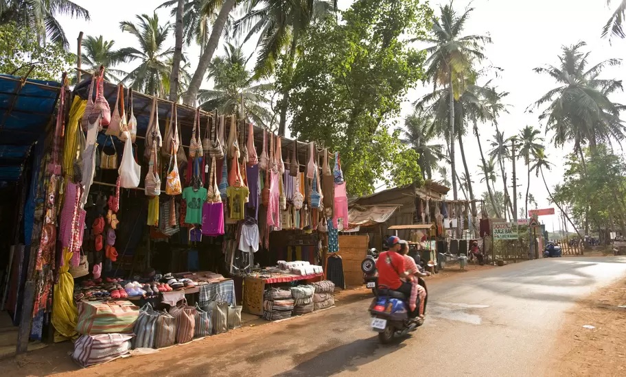 Roadside stalls in Goa hung with bags, sarongs and T-shirts beneath coconut palms as a scooter passes