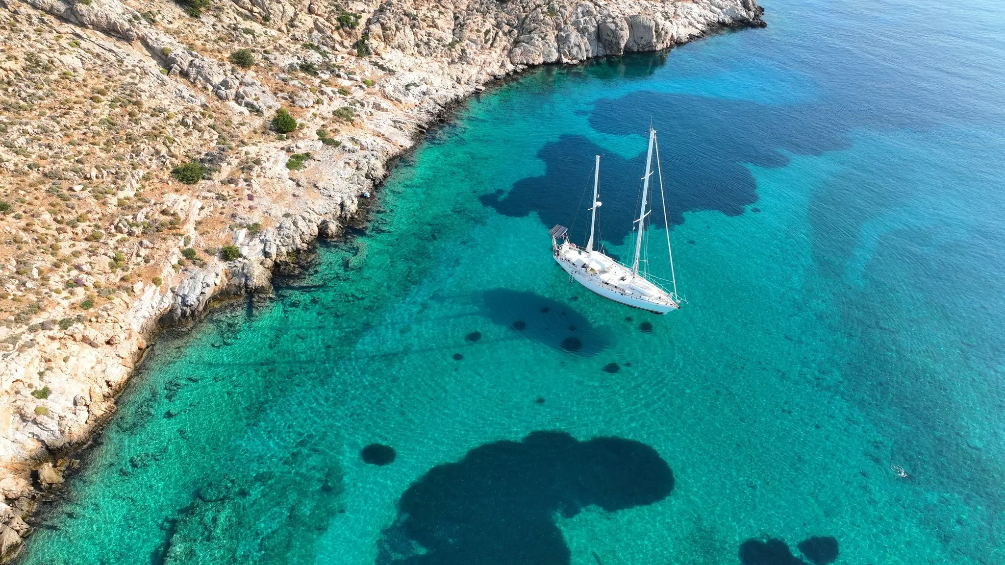 Aerial drone photo of luxury sail boat anchored in paradise bay of Ornos in island of Mykonos, Cyclades, Greece