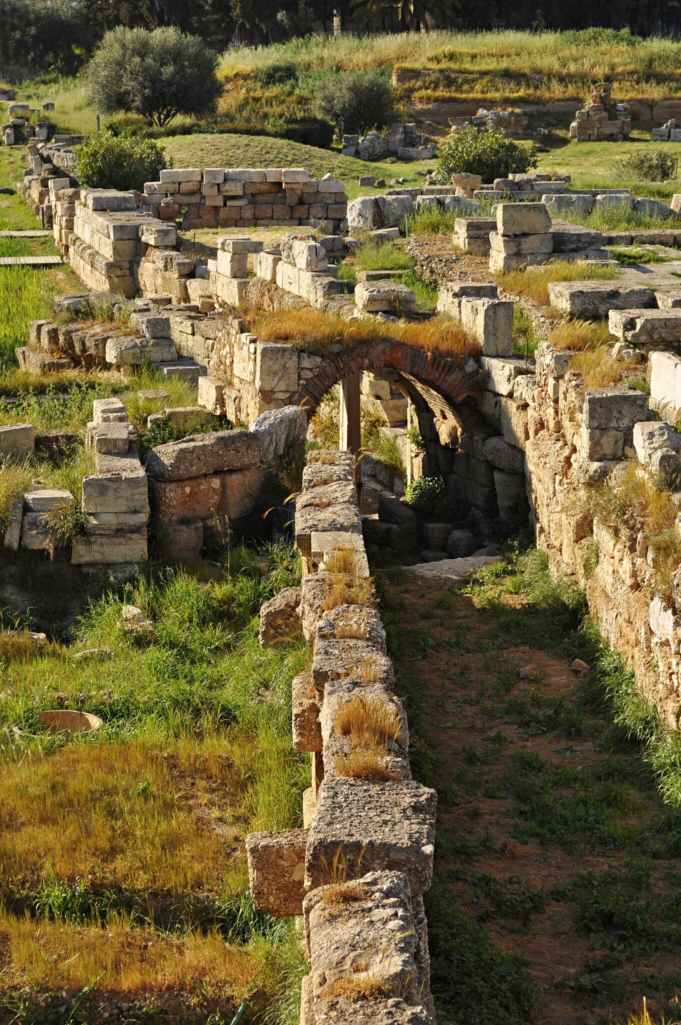 The ruins of the Ancient Kerameikos cemetery are covered in lush green grass in Athens.