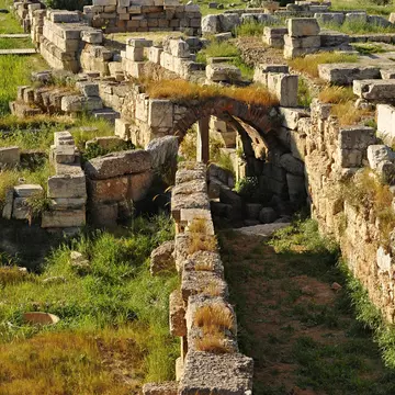 The ruins of the Ancient Kerameikos cemetery are covered in lush green grass in Athens.