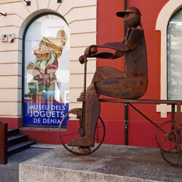 DENIA, SPAIN – JANUARY 28 2019:The exterior of the toy museum 'Museo del Juguete' in the old train station of Denia. With a sculpture of corten steel that depicts a child on a tricycle , License Type: media, Download Time: 2025-10-16T23:15:19.000Z, User: LP_YKhanna, Editorial: true, purchase_order: 65050 - Digital Destinations and Articles, job: Lonely Planet, client: App Content, other: Yuvraj Khanna