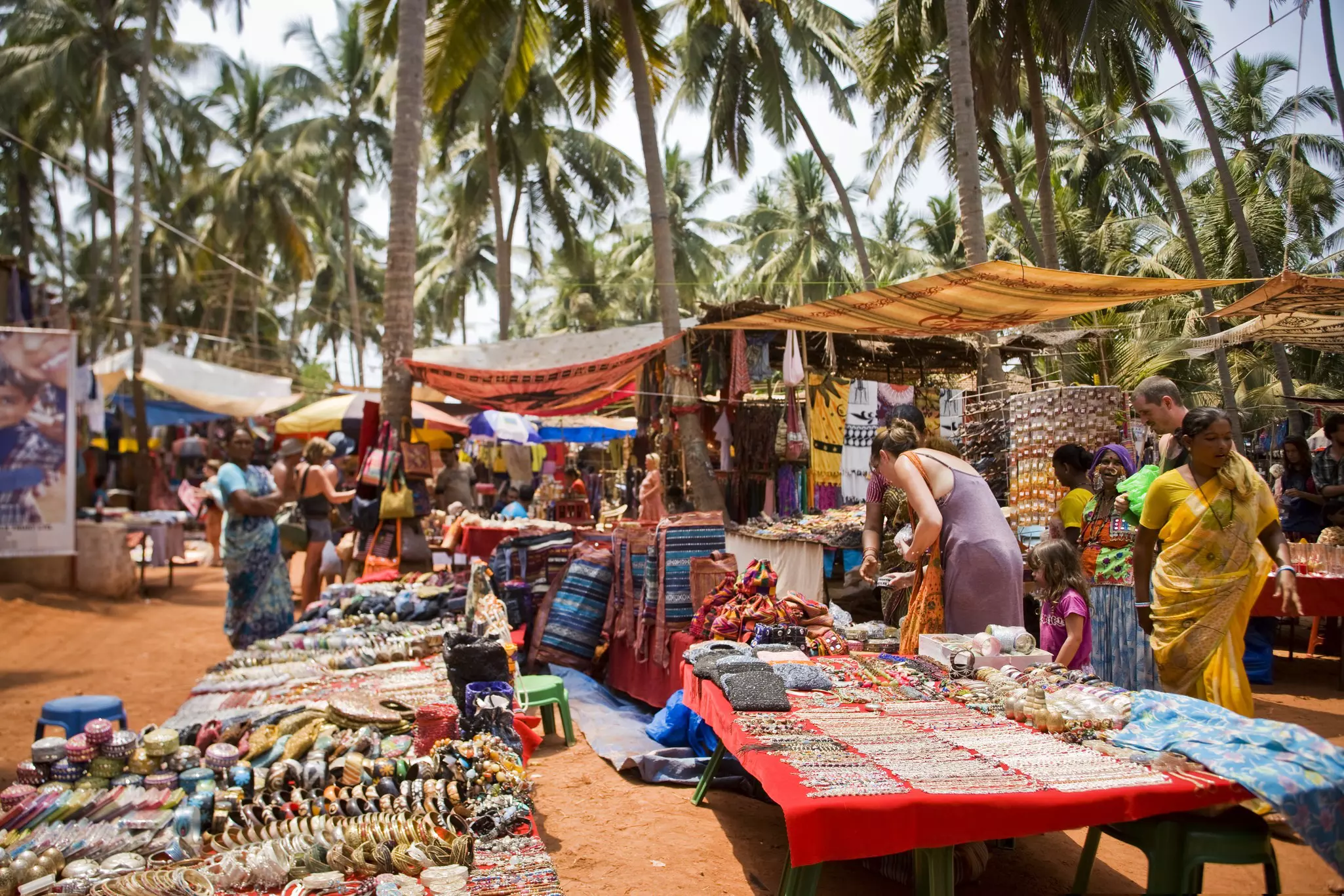 Tourists looking at handicrafts at Anjuna's Wednesday flea market, Goa, India.