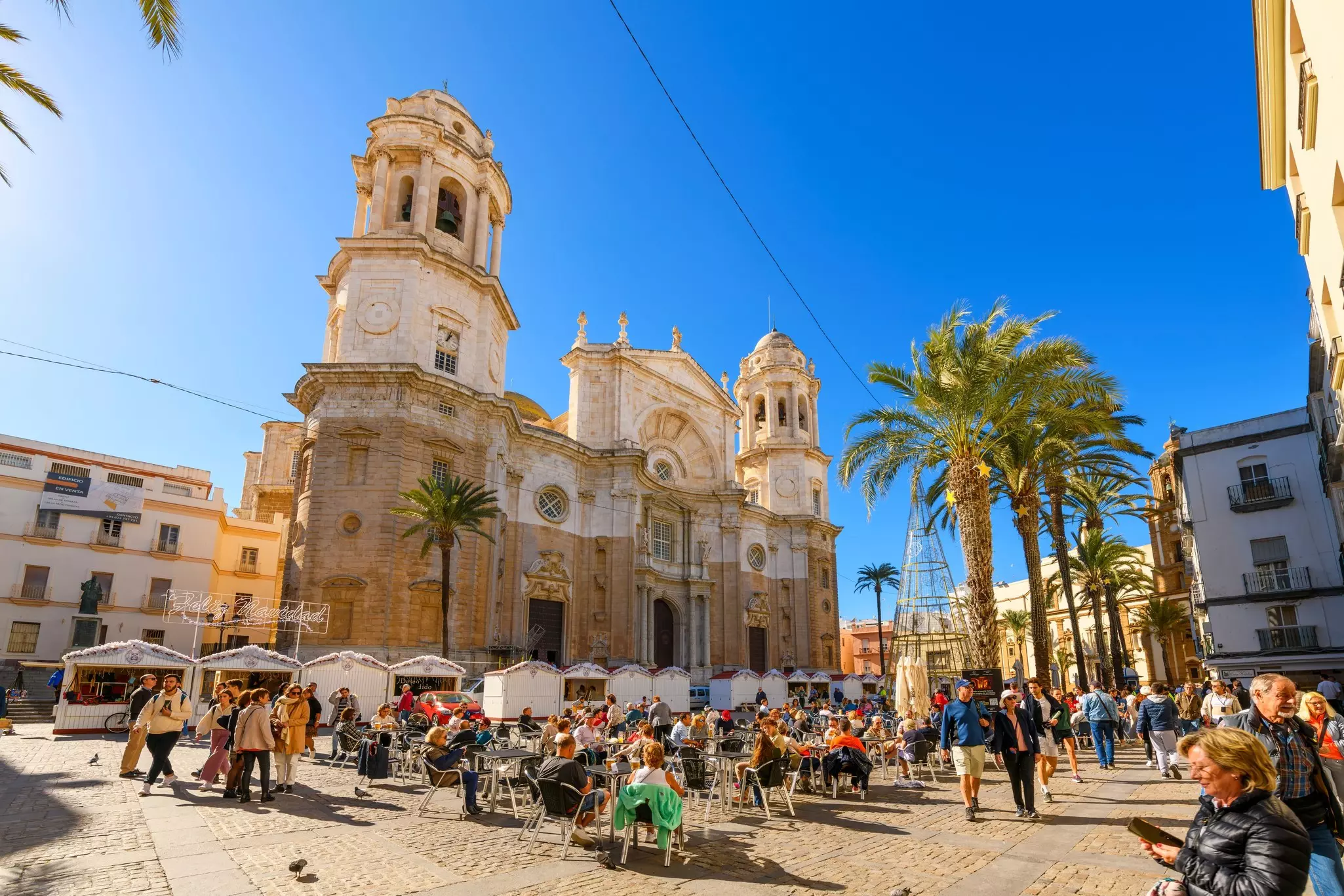Tourists dine in the sun at in a square near a cathedral