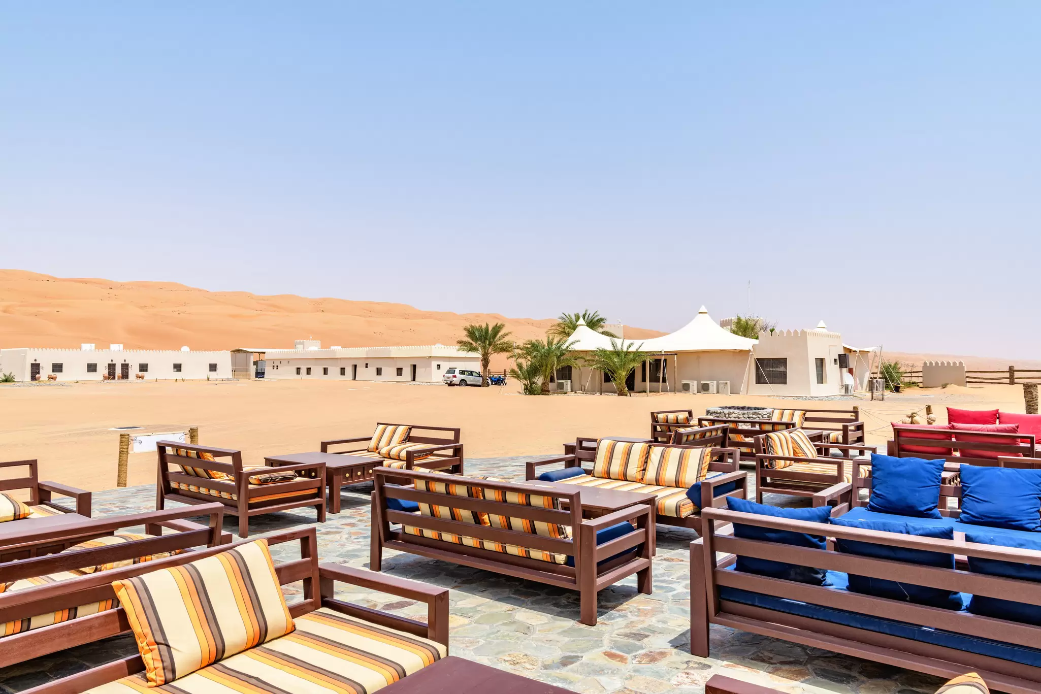 A Bedouin camp in Sharqiya Sands, with neat rows of tables and chairs on the orange desert sand
