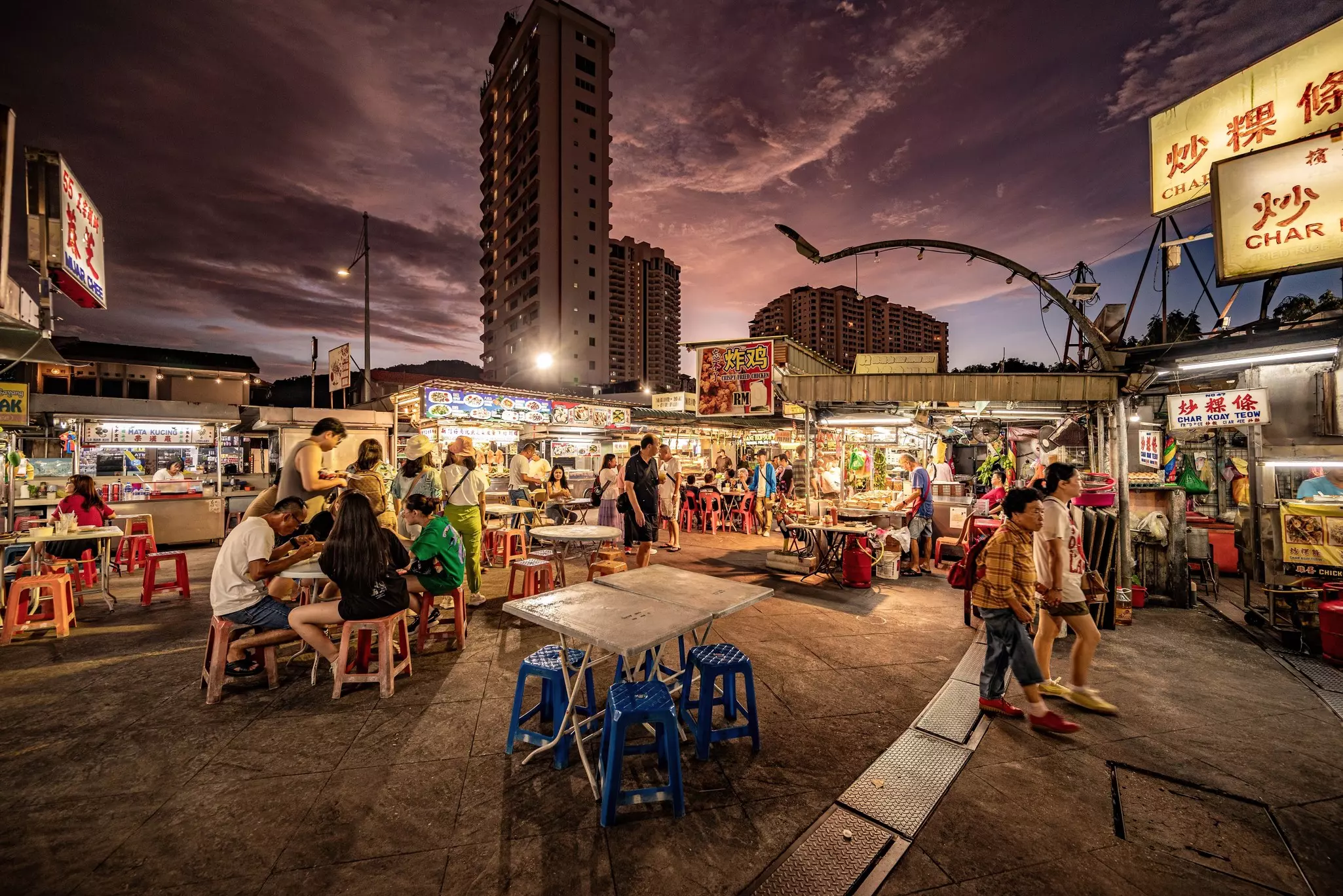 Tables are set up in a plaza at a night market in a city.