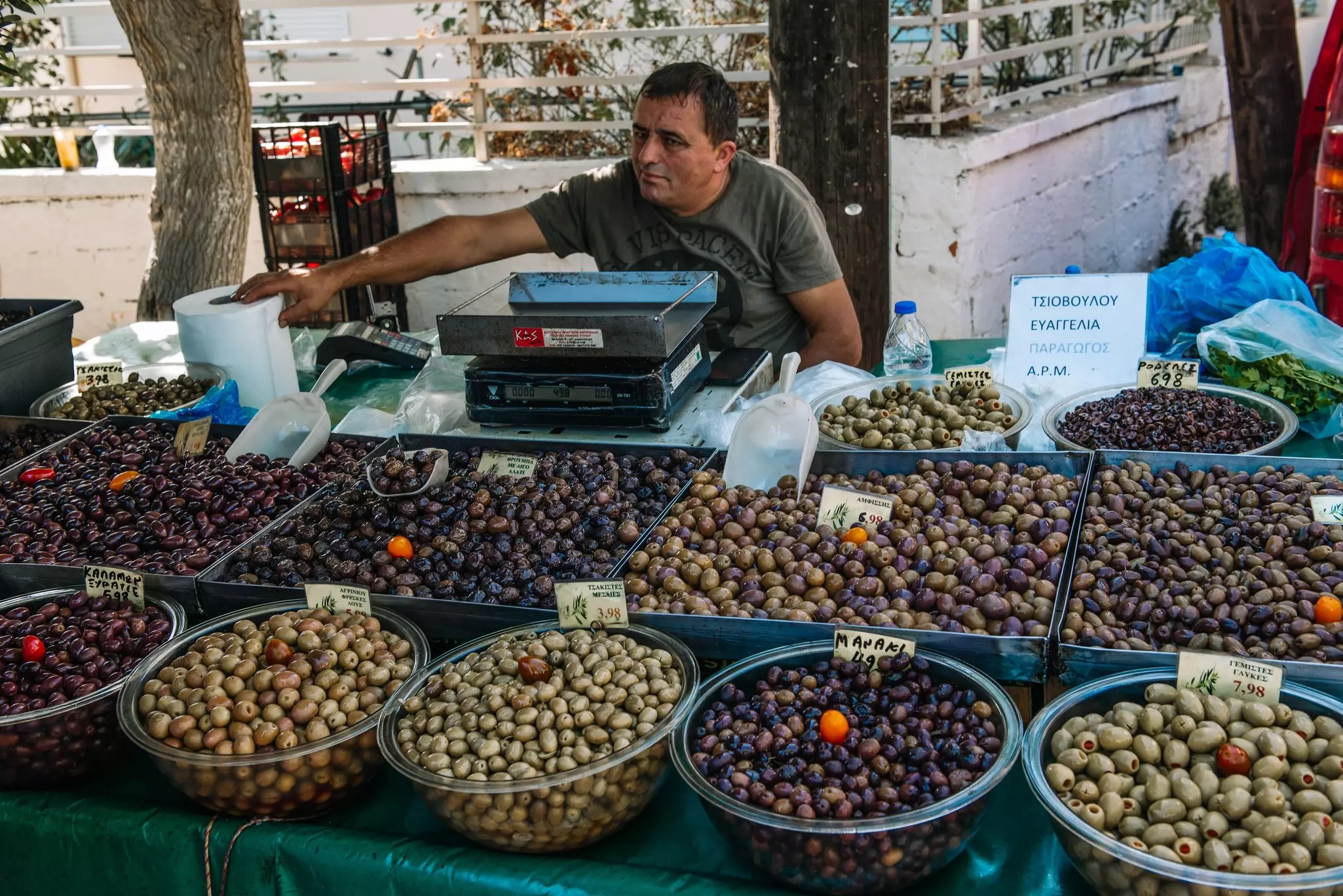 A vendor sells different varieties of marinated olives at a city market.