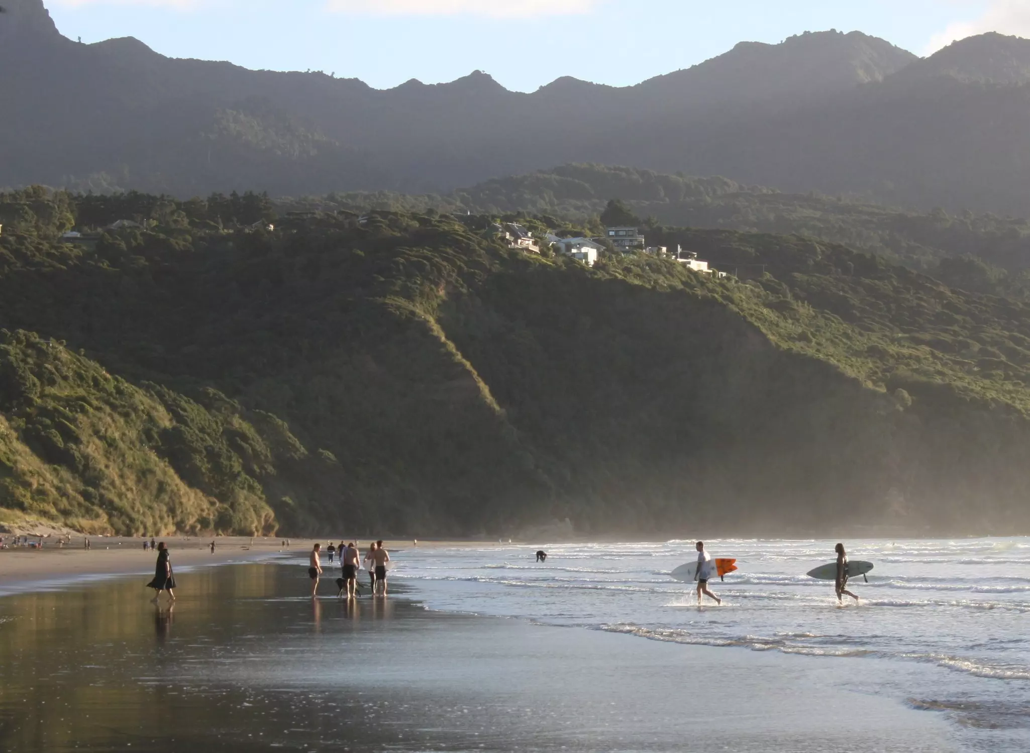 Surfers on the beach in Raglan, New Zealand