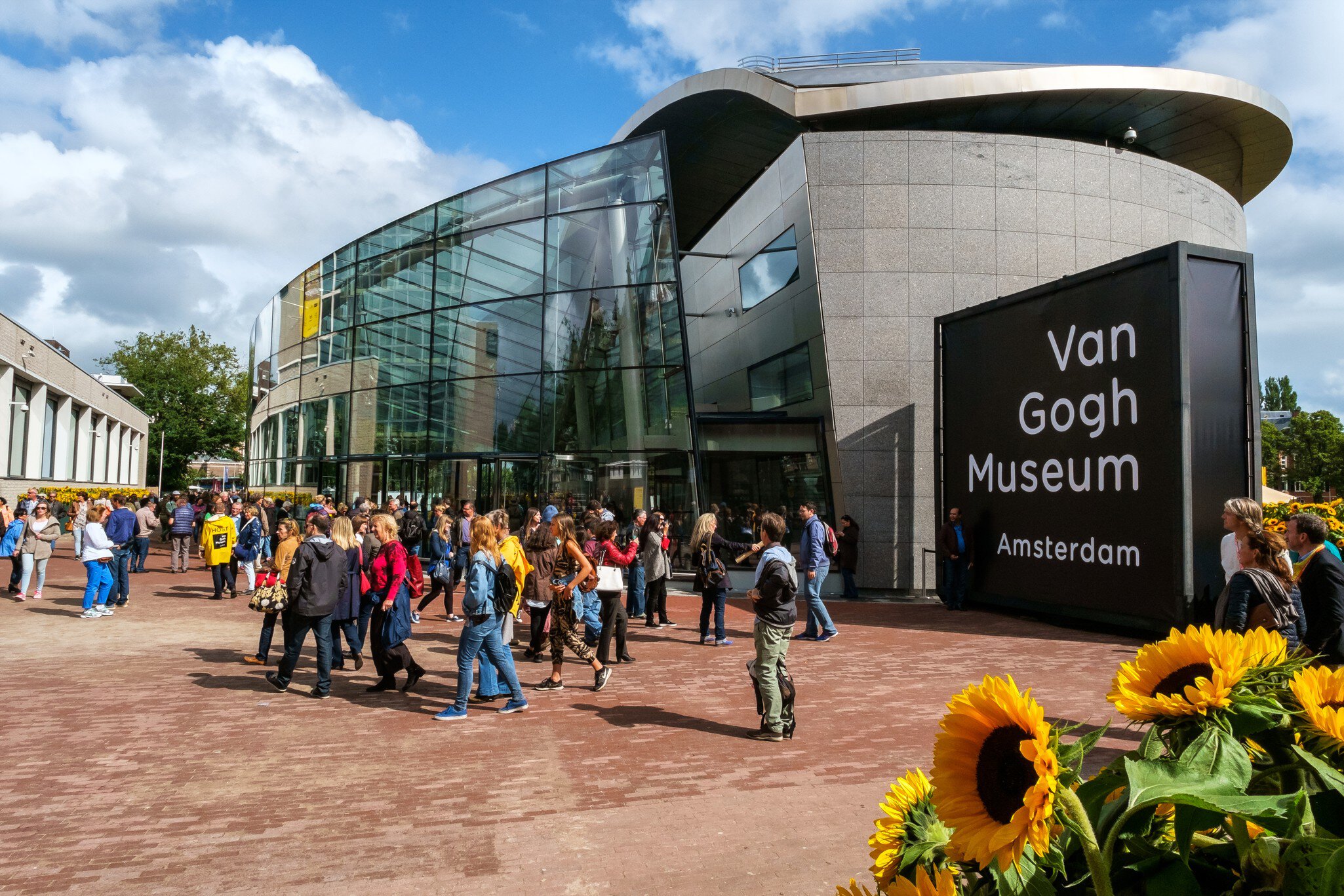 Amsterdam, the Netherlands, September 5, 2015: crowd in front of the new wing of the Van Gogh Museum with sunflowers in the foreground  License Type: media  Download Time: 2021-09-21T18:01:56.000Z  User: Norma.PrauseBrewer_LonelyPlanet  Is Editorial: Yes  purchase_order:   