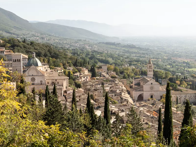 The stone town of Assisi viewed from its hilltop, with green hills in the background