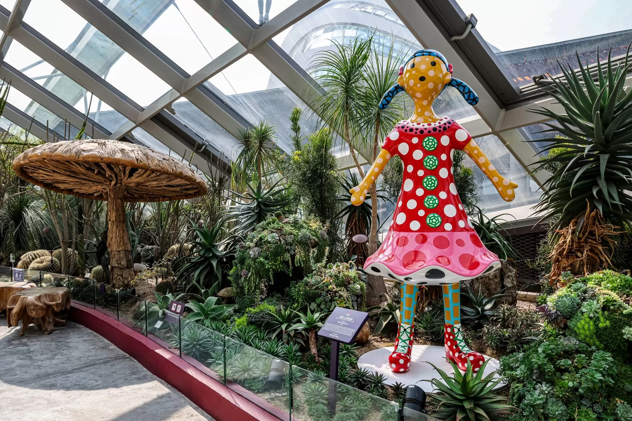 A large-scale sculpture of a girl covered in polka dots standing within a lush garden: "Kei-Chan" by Yayoi Kusama in Gardens by the Bay, Singapore