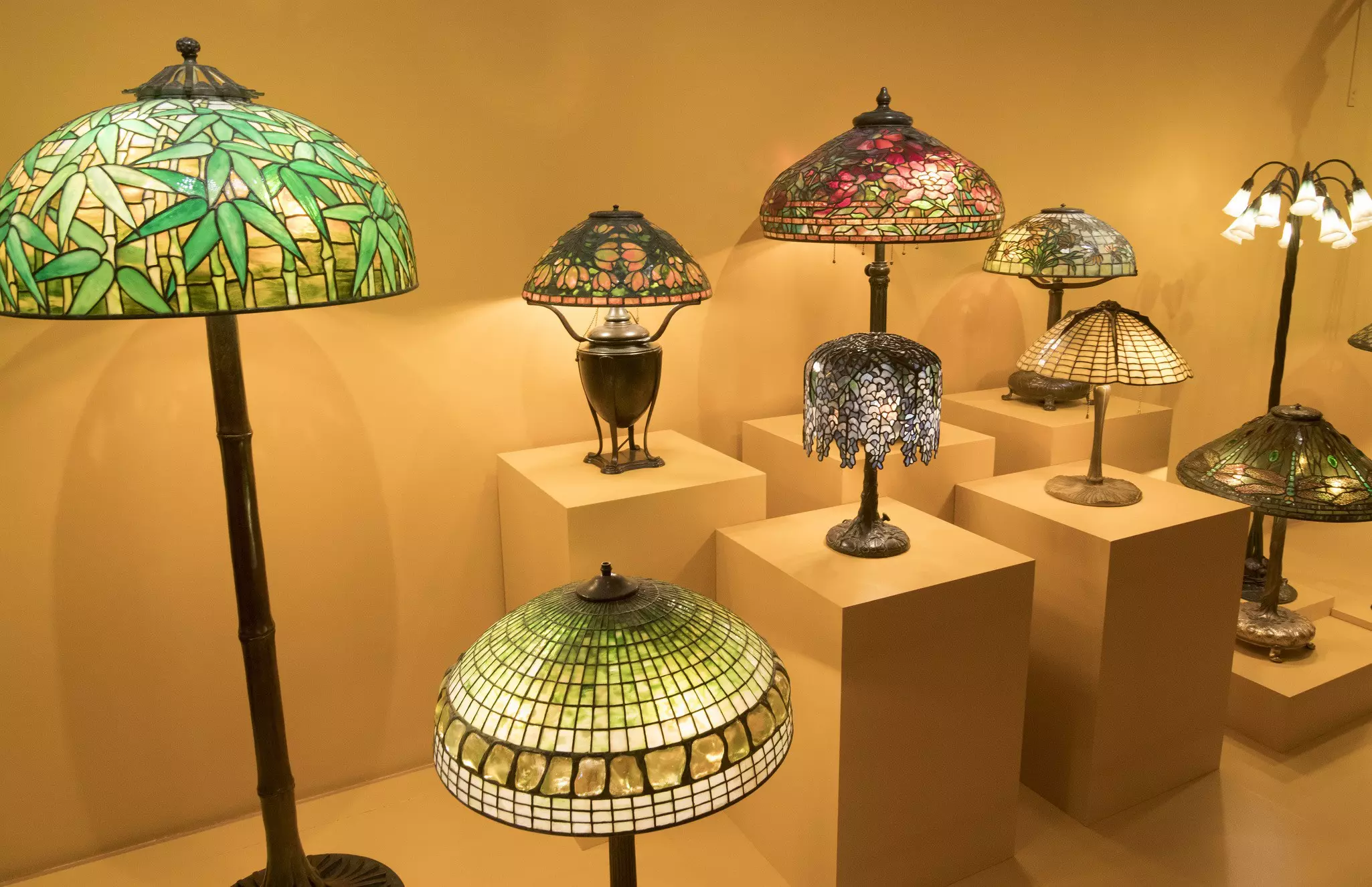 Lamps of various sizes with colorful, round, stained glass shades on display in a museum