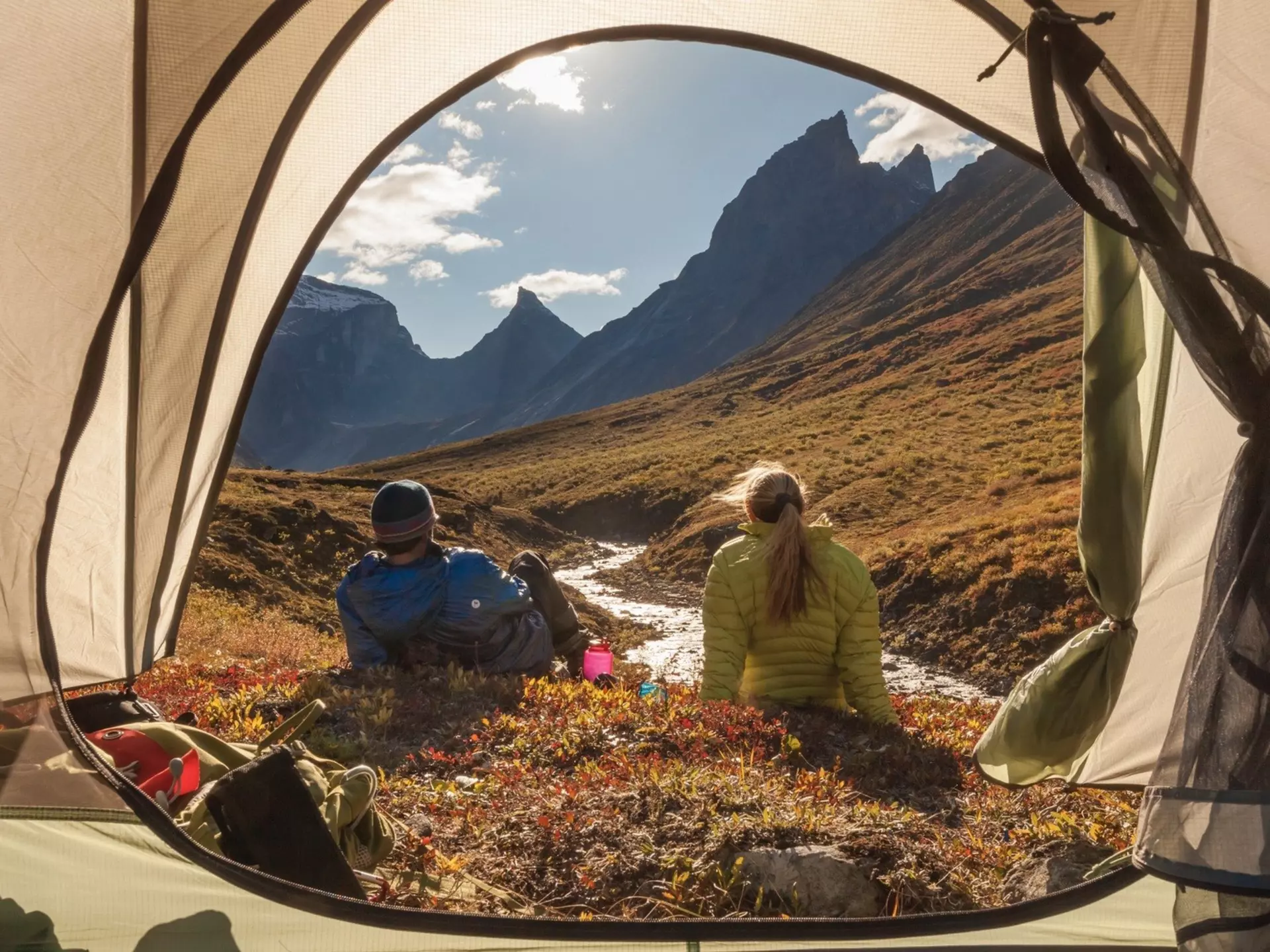 Two campers sit outside their tent admiring the view of the Brooks mountains in Alaska.