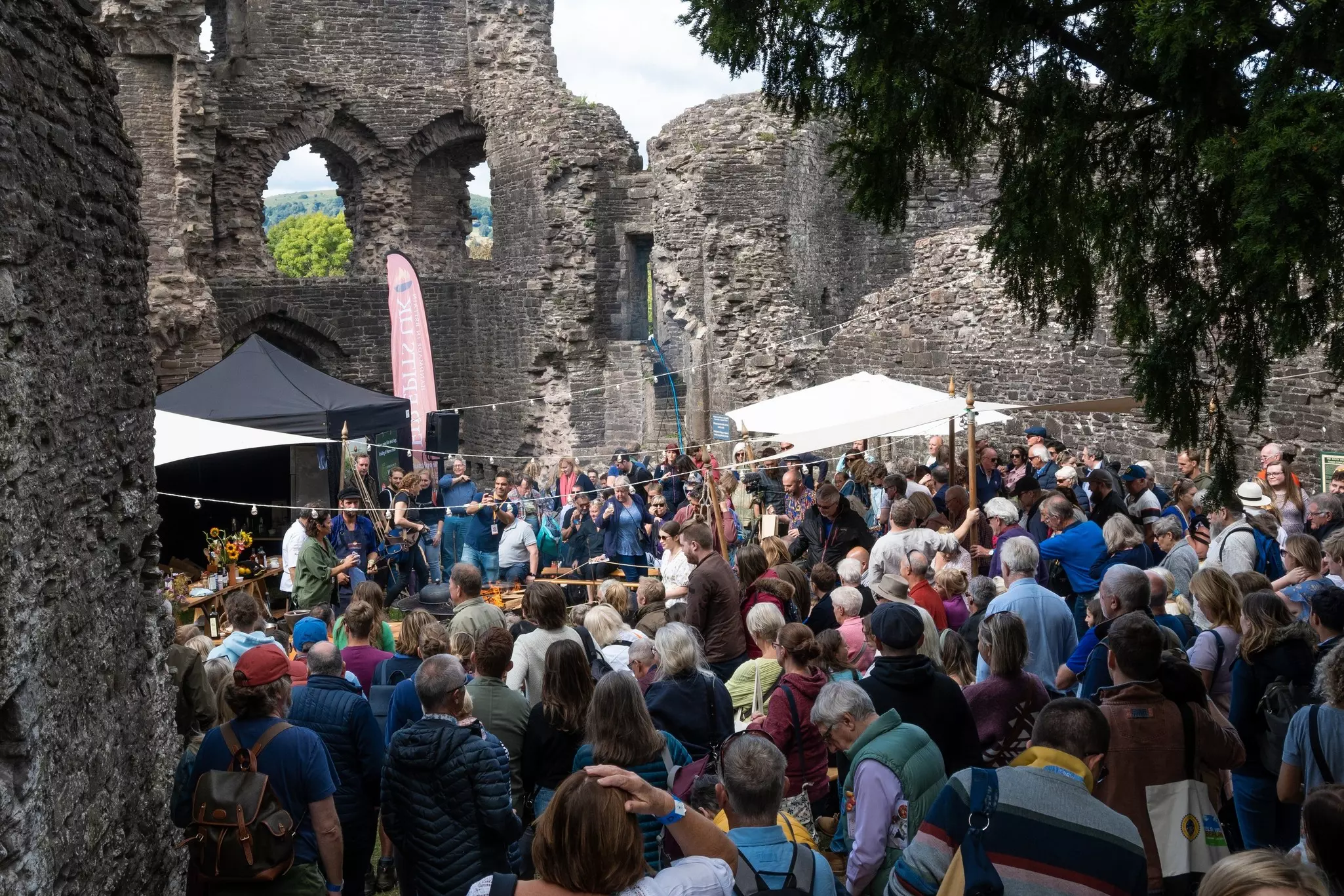 A crowd of people gathers at a festival taking place in the historic ruins of a castle.