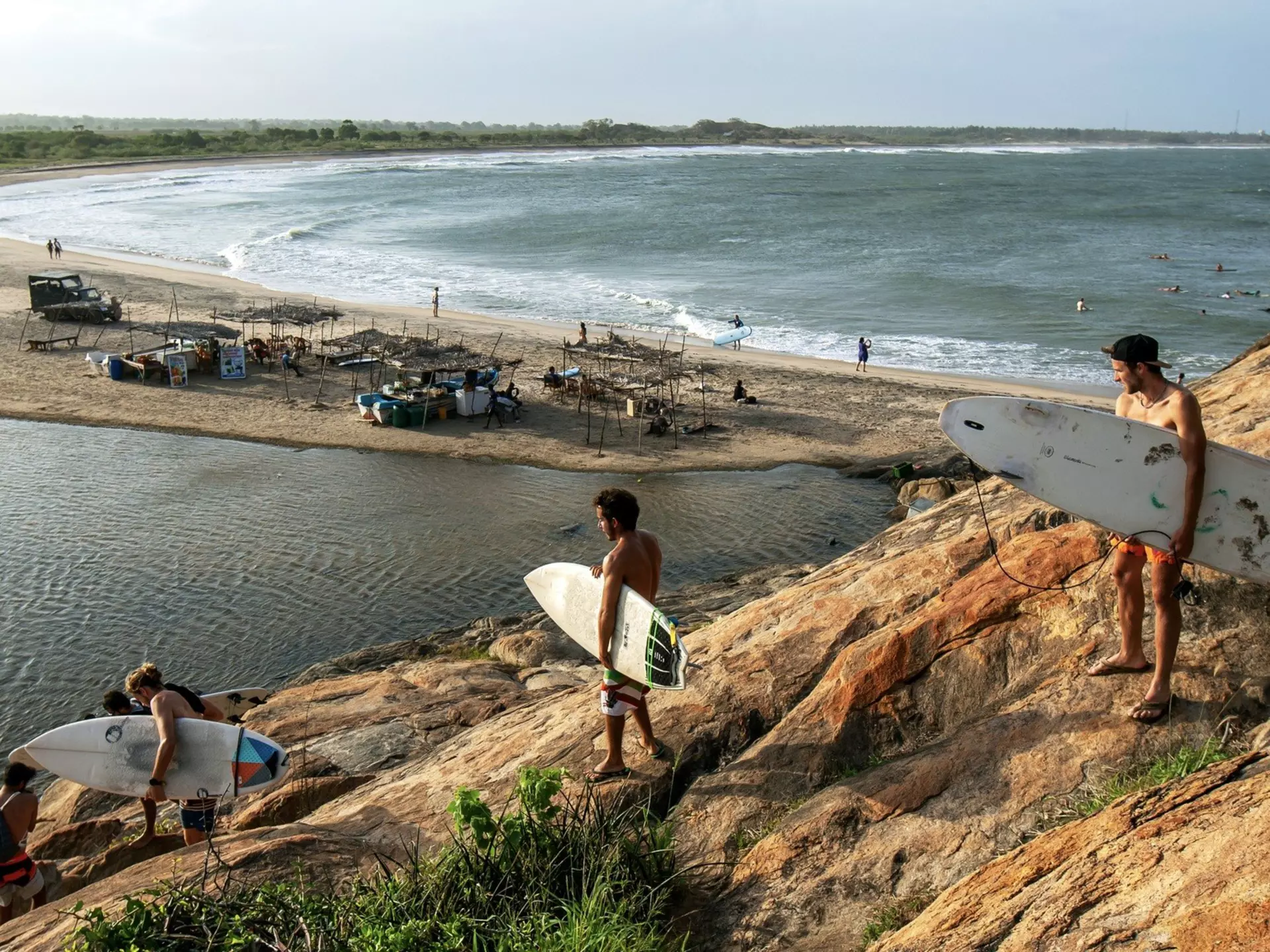 A group of surfers climb down Elephant Rock towards the beach for a surfing session.
