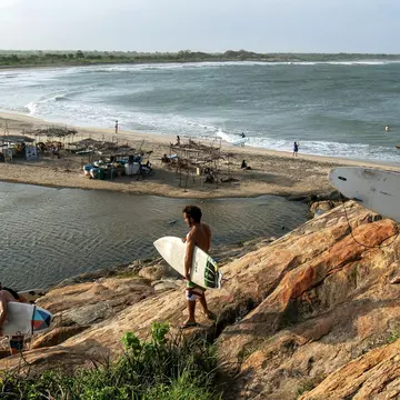 A group of surfers climb down Elephant Rock towards the beach for a surfing session.