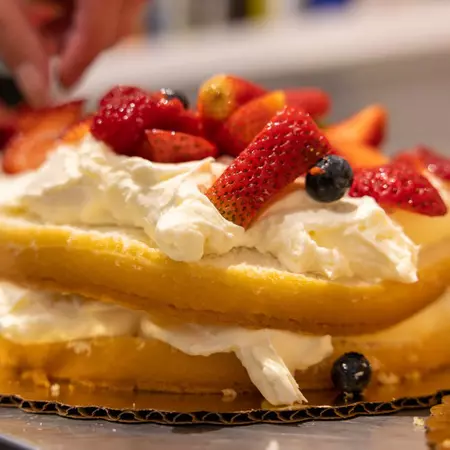 A close-up shot of cake topped with whipped cream and berries.