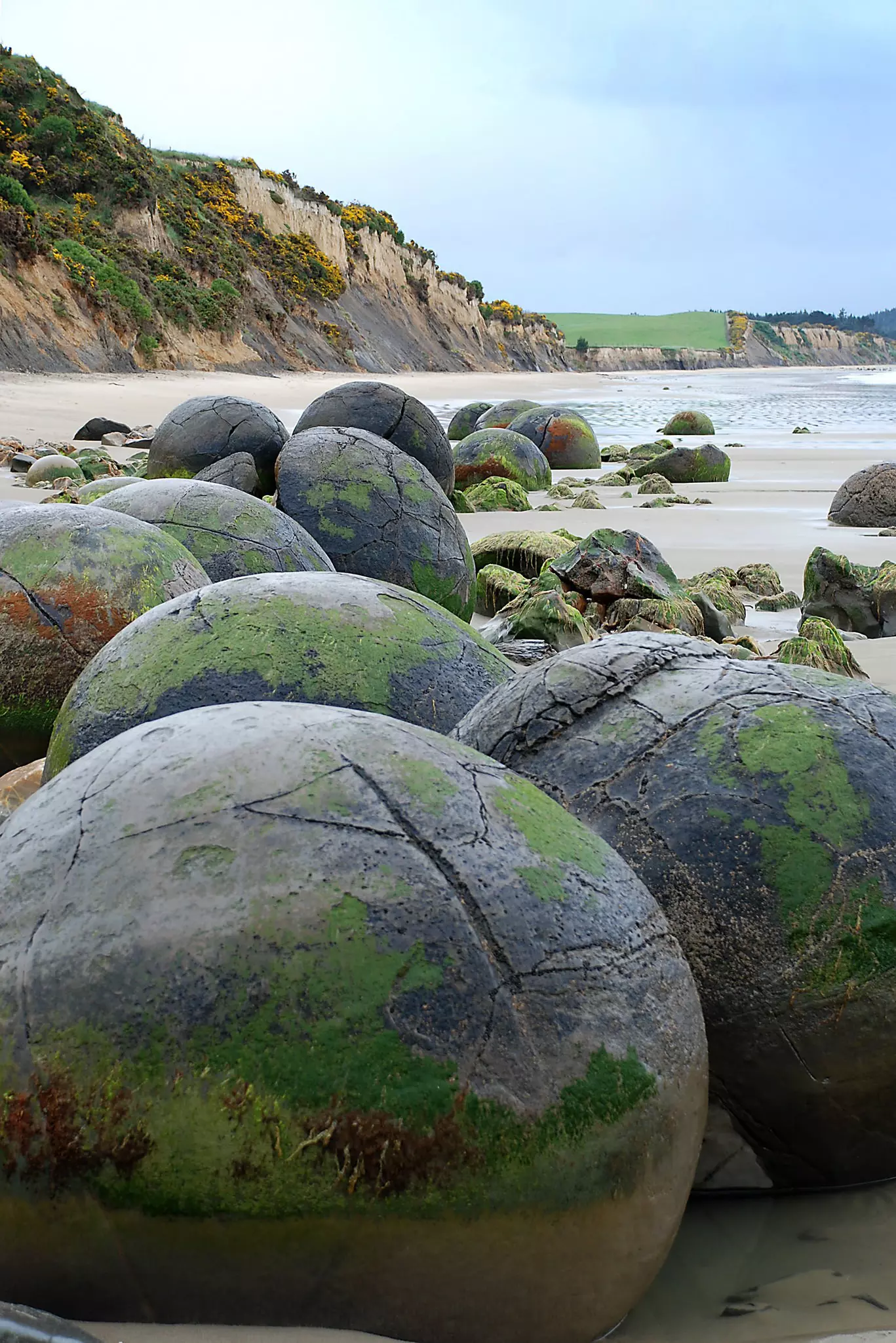A series of large round boulders on a sandy beach.