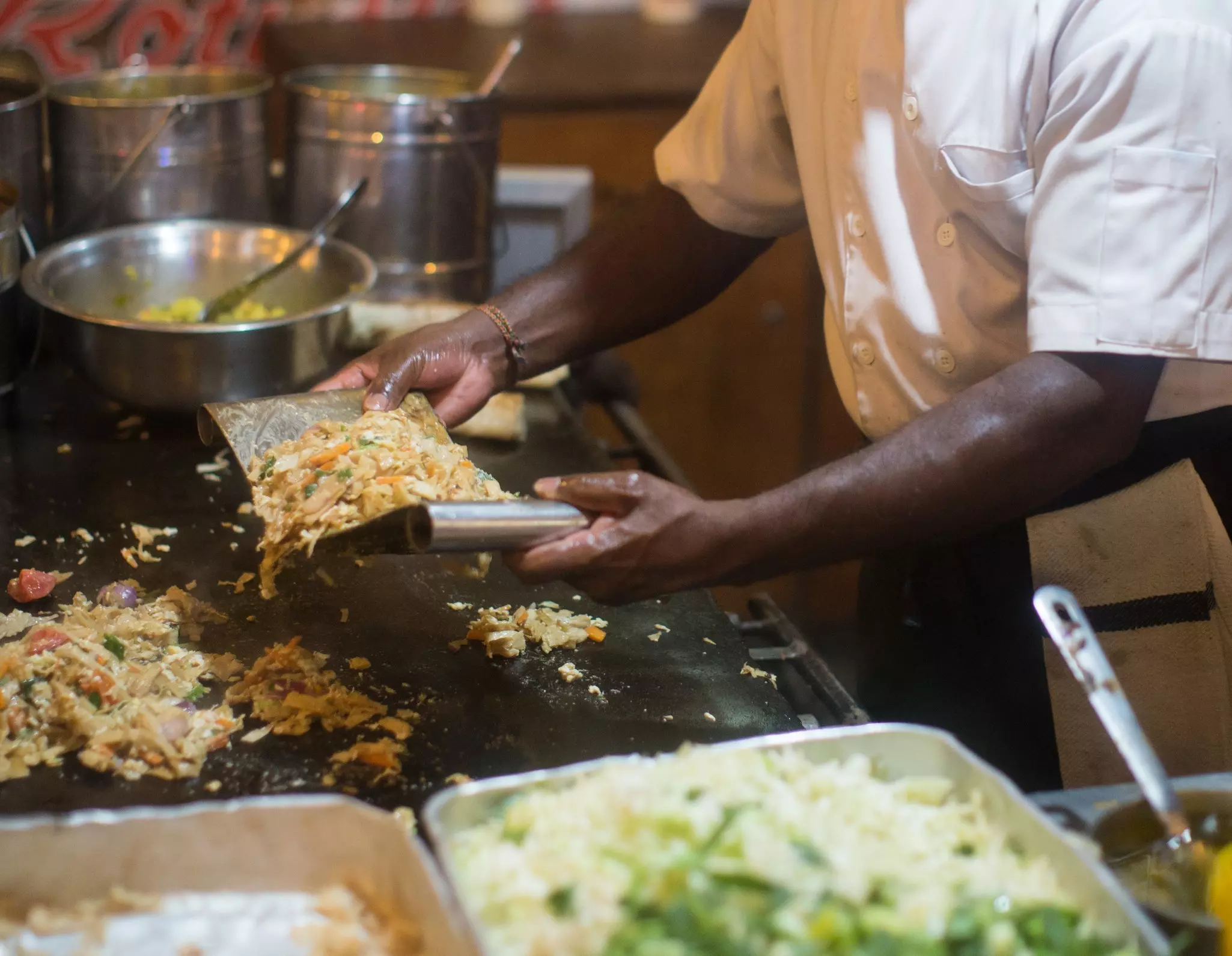 Close view of chef's arms while making a dish with chopped vegetables, eggs and meat