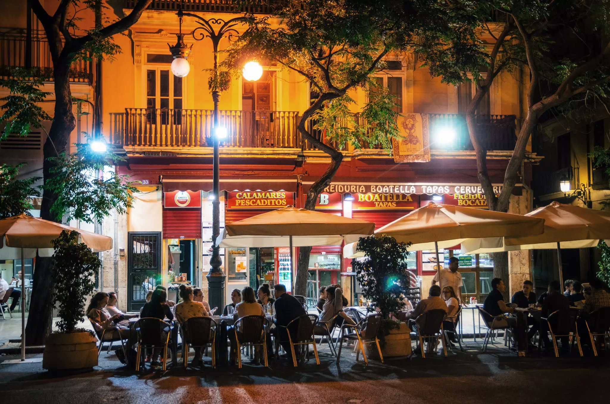 People sit outside a bar under trees at night