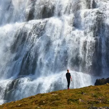 Person standing at the Dynjandi waterfall, also known as Fjallfoss, located on the Westfjords peninsula in northwestern Iceland.  License Type: media  Download Time: 2021-11-08T12:05:46.000Z  User: aniabartoszek  Is Editorial: No  purchase_order:   