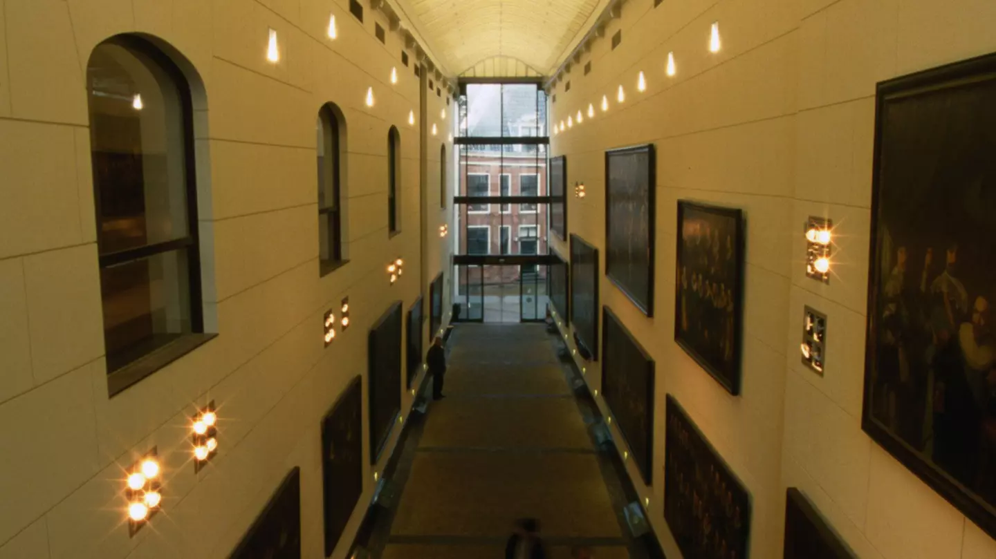 A shot downwards of a long hallway lined with paintings