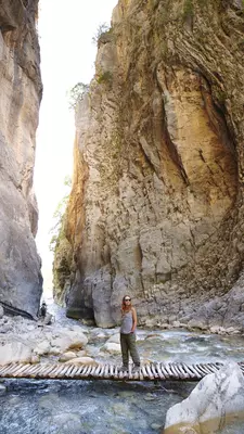 Female guide crosses the river in front of the ‘Iron Gates’ passage in the Samaria Gorge.