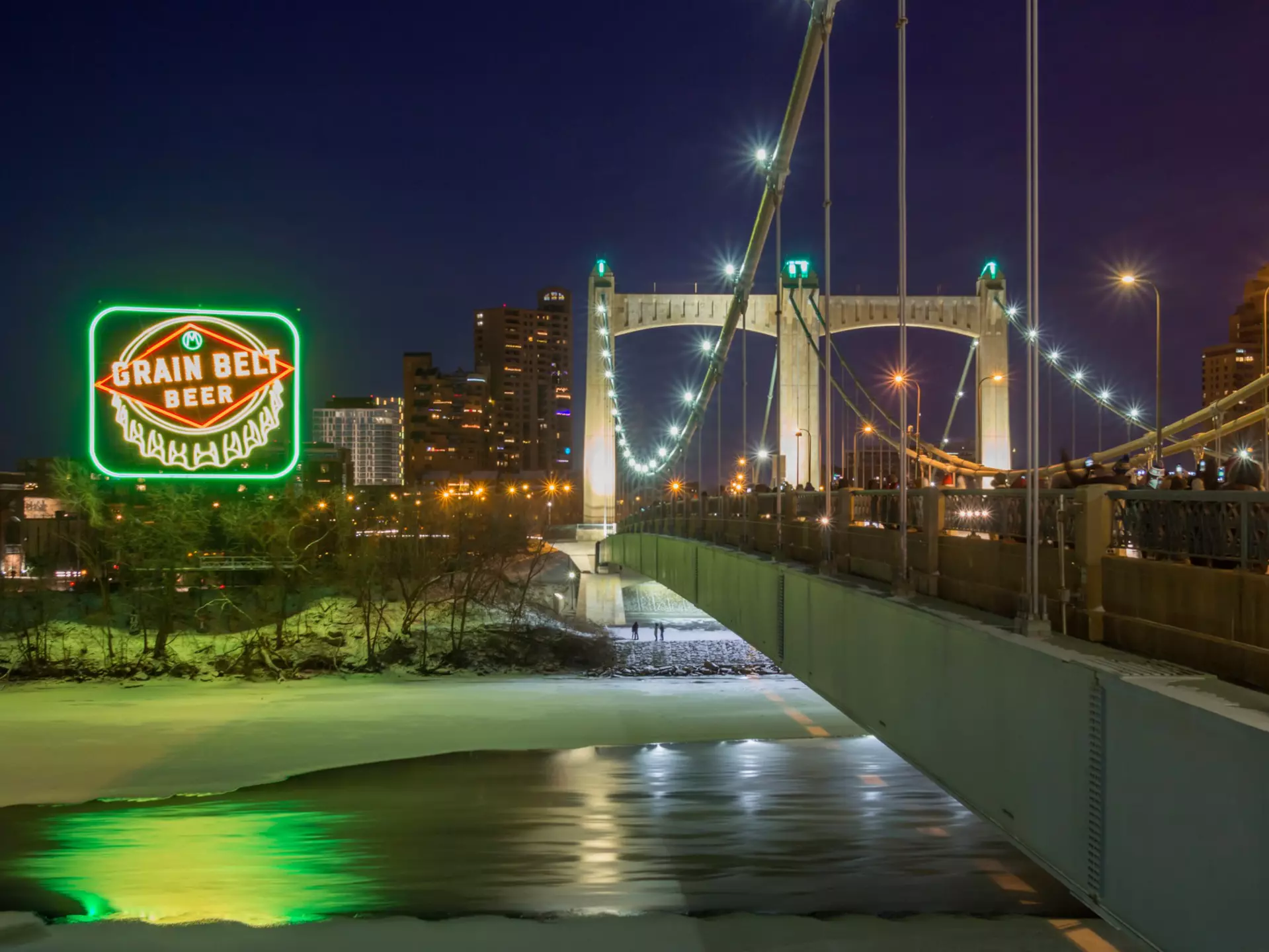 MINNEAPOLIS, MN - DECEMBER 2017 - A Long Exposure Night Shot of the Inaugural Relighting of the Iconic Grain Belt Beer Sign along the Frozen Mississippi River by the Hennepin Avenue Bridge in Winter  License Type: media  Download Time: 2021-08-05T14:31:47.000Z  User: AMccarthy_lonelyplanet  Is Editorial: Yes  purchase_order:   