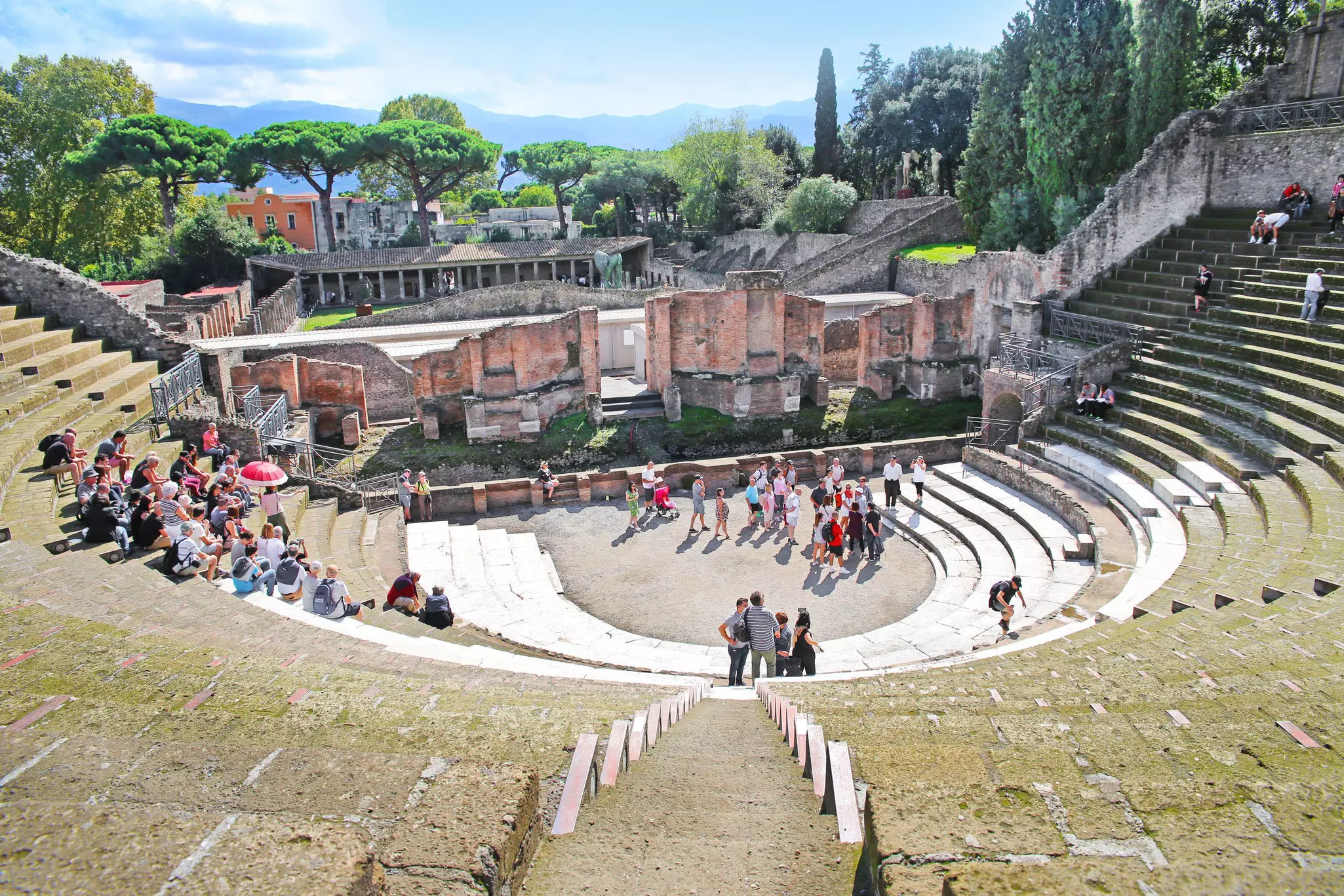 A vast ancient amphitheater with tourists walking around