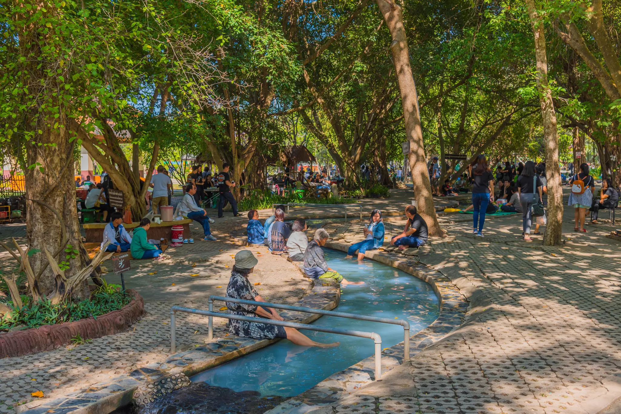 Bathers dipping their feet in the hot springs at San Kamphaeng near Chiang Mai, Thailand. 
