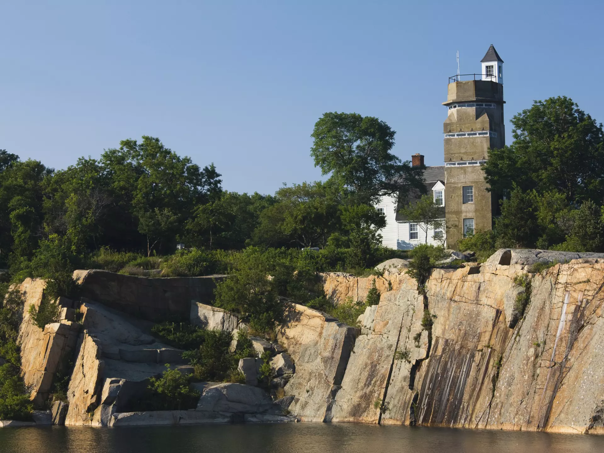 A WW2 submarine lookout tower and an old granite quarry above a body of water at Halibut Point State Park in Massachusetts.