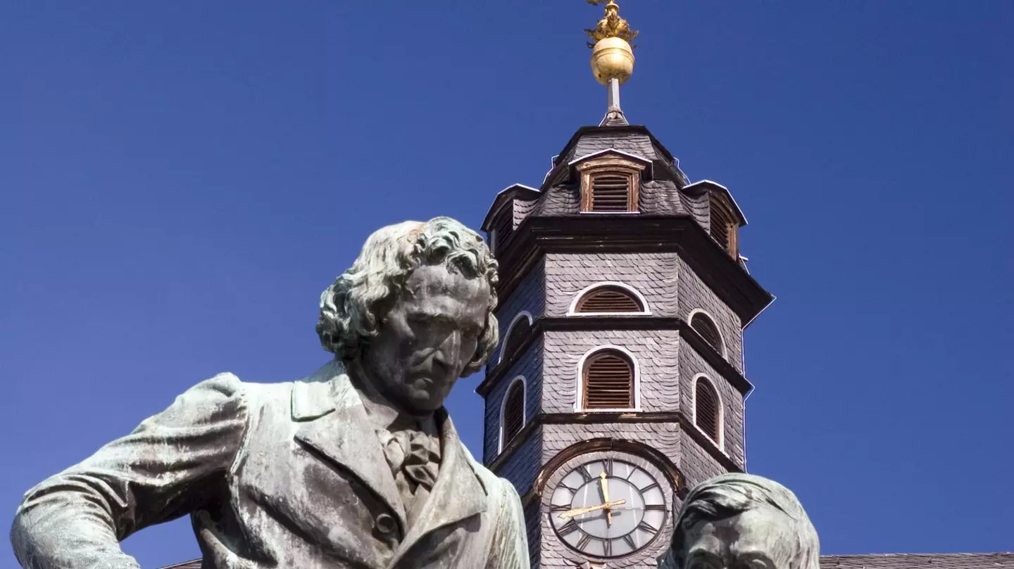 The author dressed in blue jeans and a plaid shirt, next to a faded barn wall