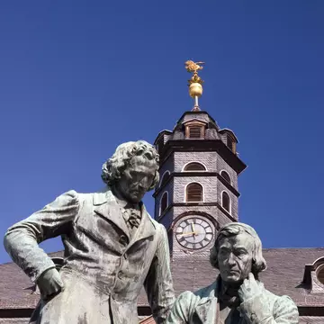 The author dressed in blue jeans and a plaid shirt, next to a faded barn wall