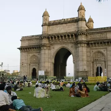 People sit on the lawn by the Gateway of India in Mumbai, India. 