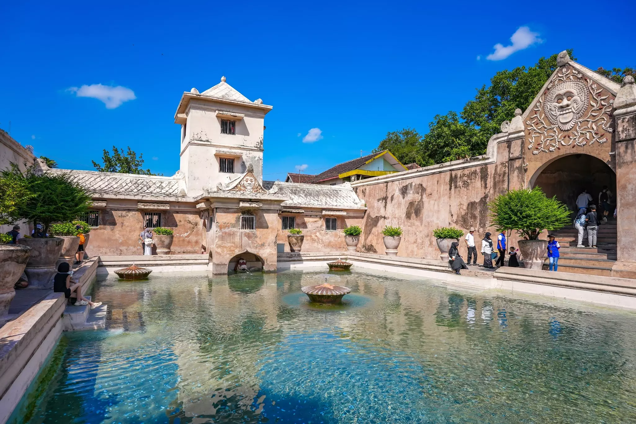 A large water feature in front of a palace. Tourists are visiting the grounds