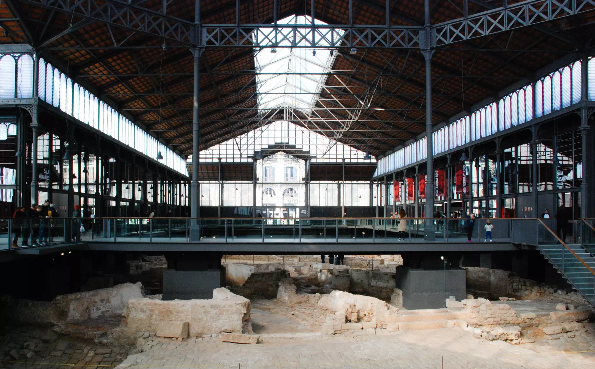 Exposed archaeological layers below a modern framed structure in Barcelona.