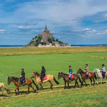 Mont Saint Michel / France - July 19 2016 : Horse riding facing the monastery, License Type: media, Download Time: 2025-08-20T22:52:43.000Z, User: krista950237, Editorial: true, purchase_order: 56500 - T&R or Kids, job: Global Publishing WIP, client: A Kid's Guide to France, other: Krista Rossow