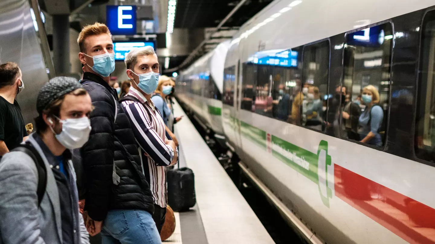 People wearing mask waiting for ICE train on platform at station (Berlin Hauptbahnhof).