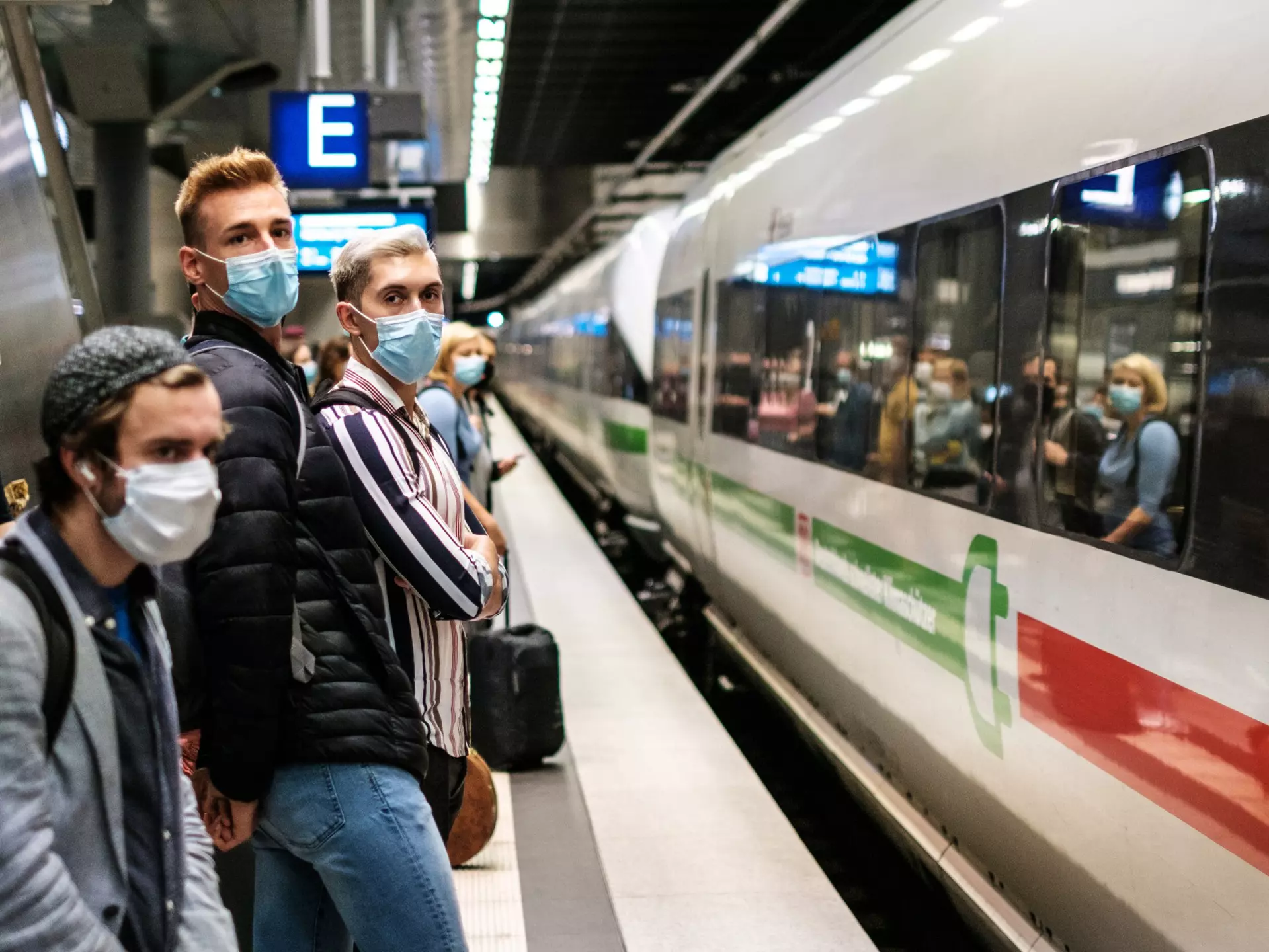 People wearing mask waiting for ICE train on platform at station (Berlin Hauptbahnhof).