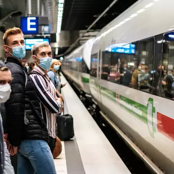 People wearing mask waiting for ICE train on platform at station (Berlin Hauptbahnhof).