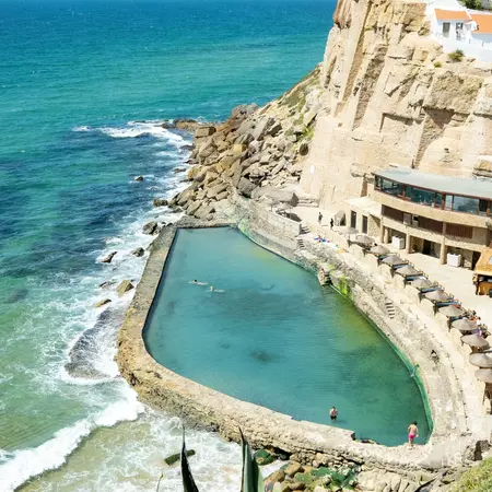 A tidal pool on a summer day with a few people swimming in it