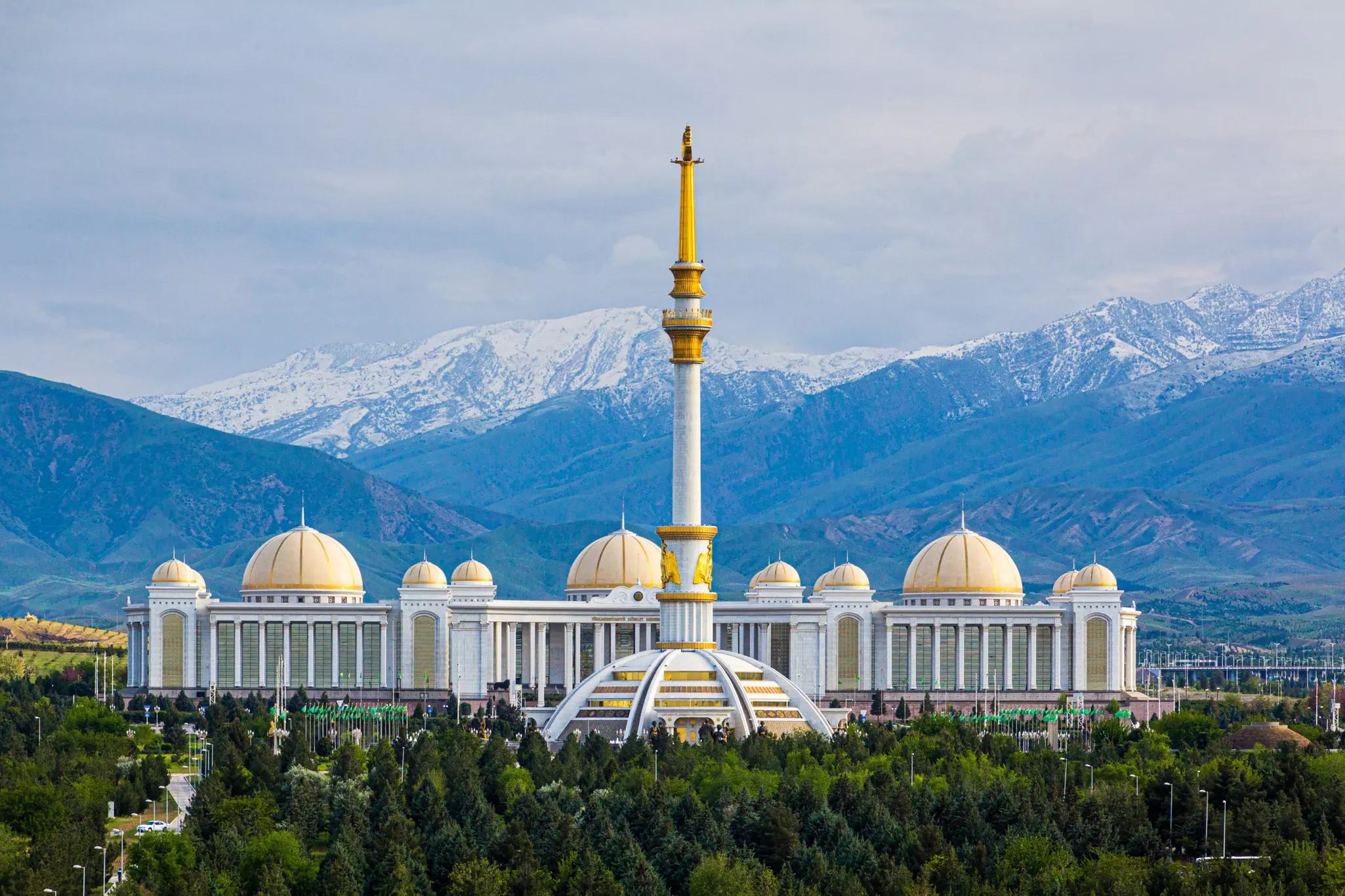 Independence Monument and National Library in Ashgabat, Turkmenistan, with mountains behind.