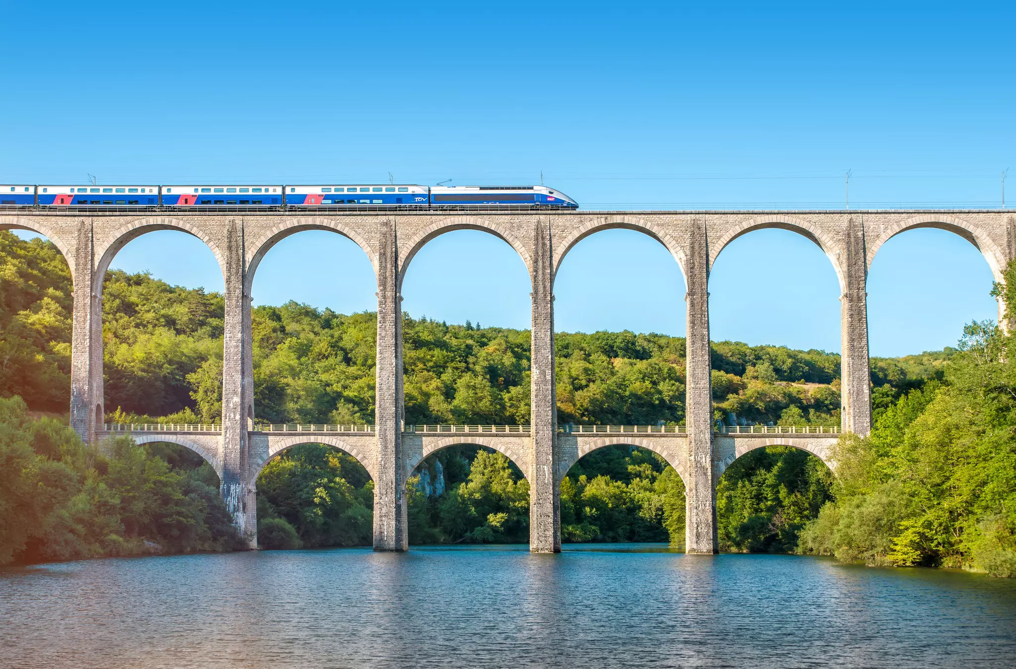 A high-speed train on the top level of a two-level bridge over a river