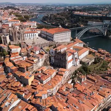 A view over the rooftops of Porto, Portugal, with the Dom Luis I bridge surrounded by buildings with terracotta tiles.