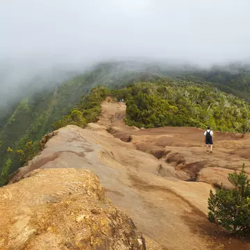 A male hiker on the Pihea Trail in Koke'e State Park on the island of Kauai, with clouds gathering above the Kalalau Valley, making the hiking trail mysterious and heavenly
