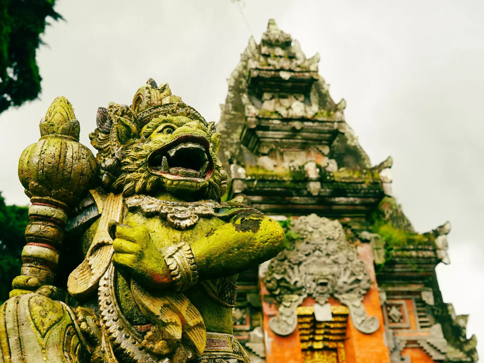A stone figure with a green mossy covering; a temple is in the background.
