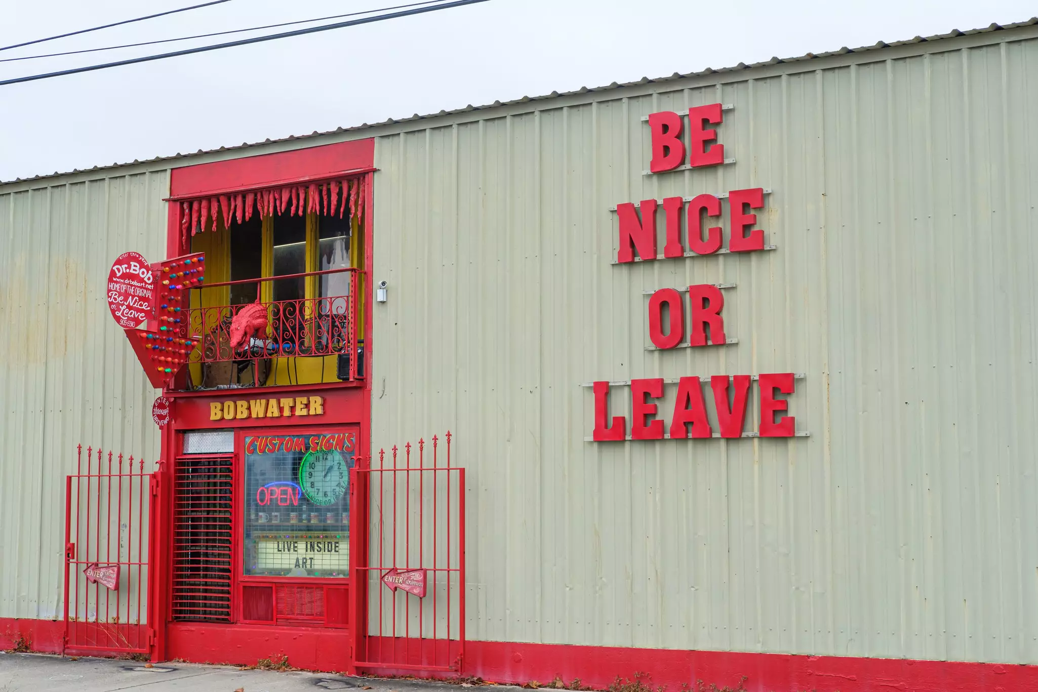 A yellow building with poetry painted on the left and a black and white image of a black girl with her arms raised in New Orleans
