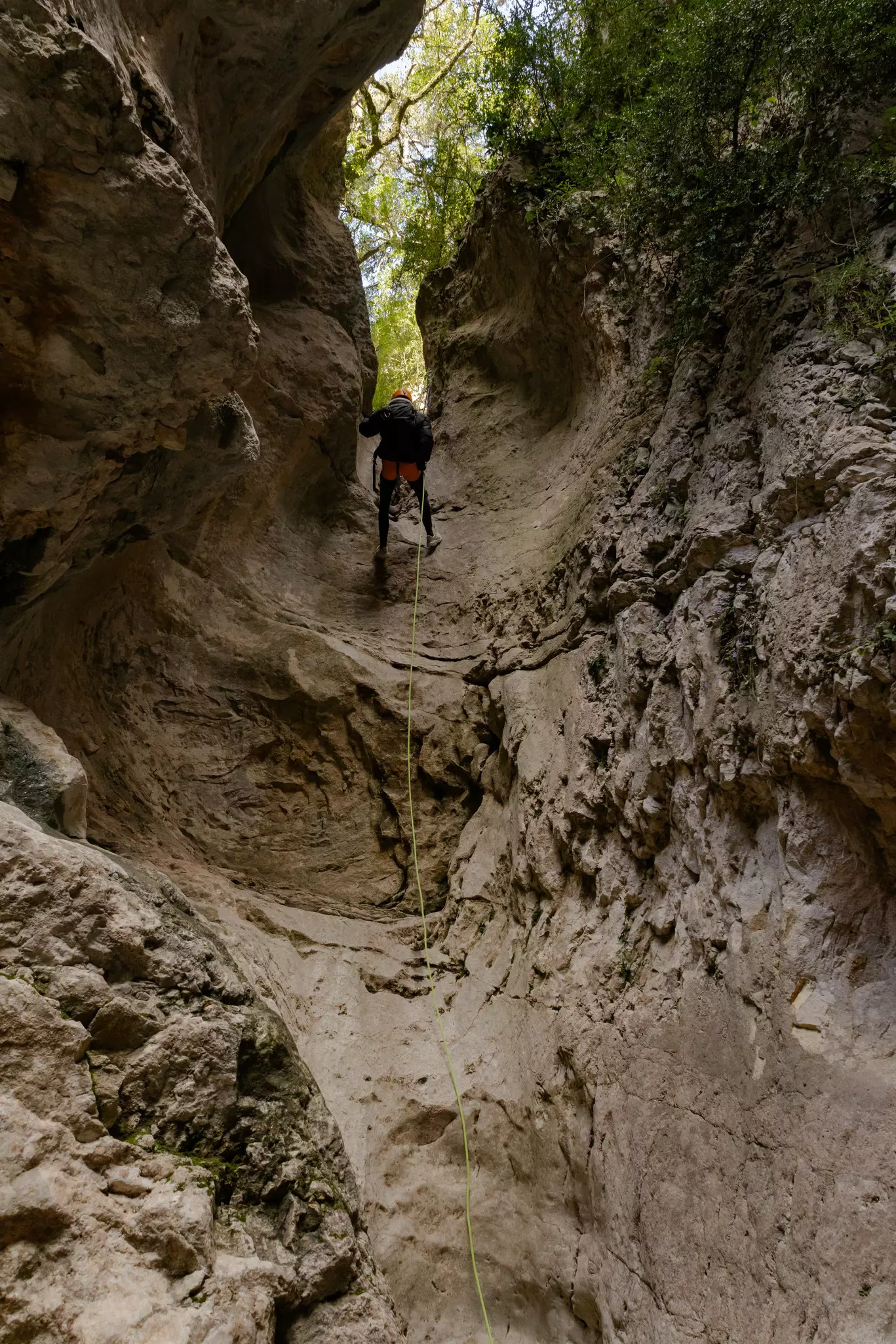 A person rappels down a rocky cliff.