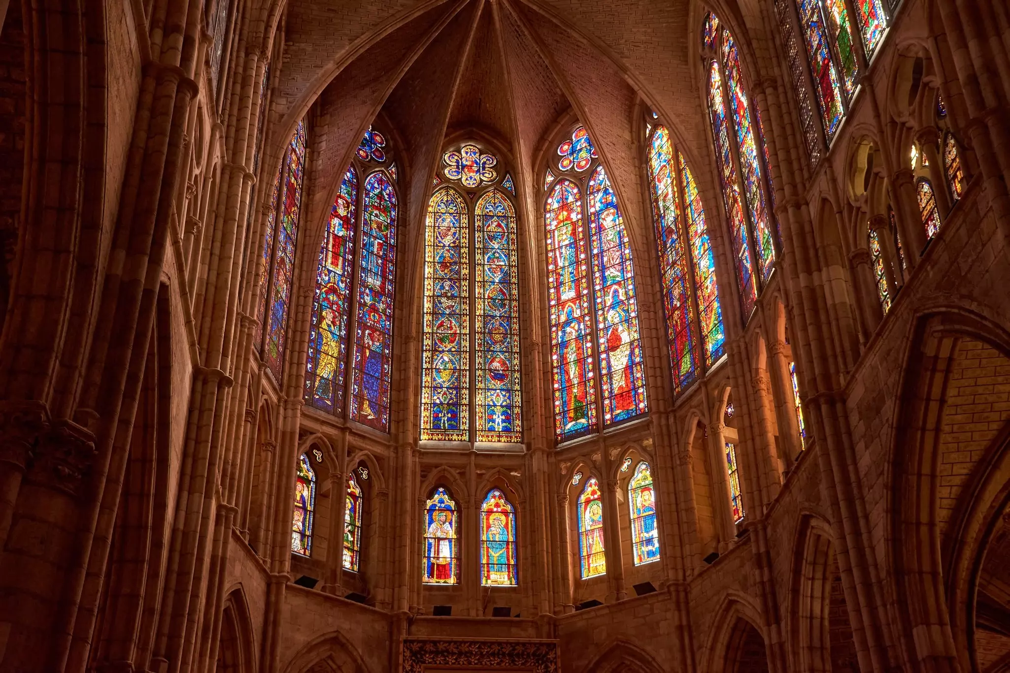 Light floods through medieval glasswork inside a vast cathedral
