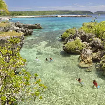 People swimming in a lagoon on Mare Island in New Caledonia.