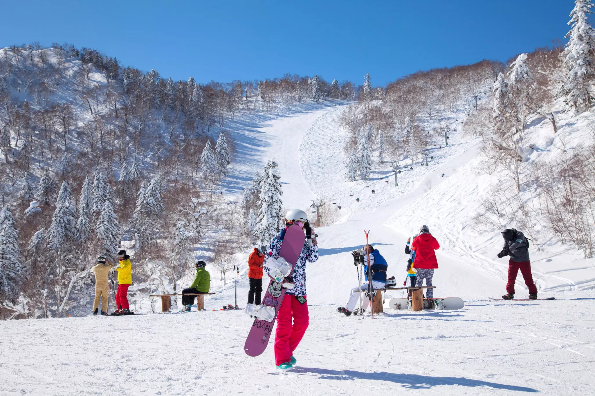 Skiers and snowboarders surrounded by snowy mountain slopes.